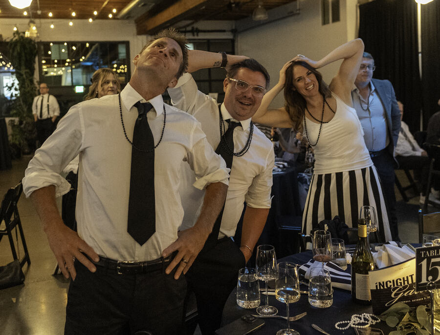 Guests with their ties loosened and hands behind their heads, laughing through a game between the tables.