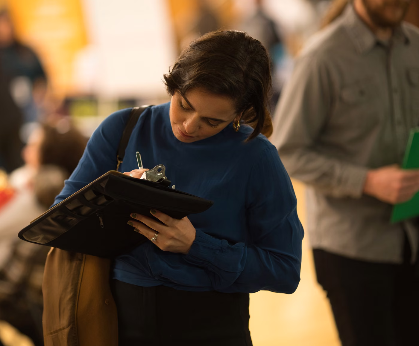 A job seeker filling in an application on a clipboard at an INCIGHT job fair.